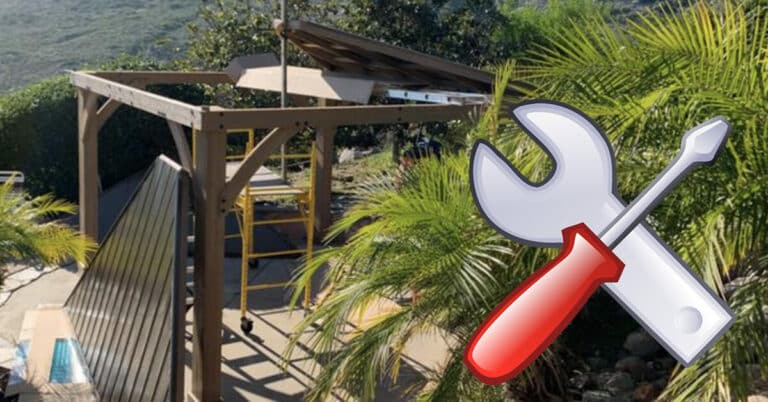 Partially constructed wooden pergola in a garden with a ladder inside, surrounded by palm trees and greenery; large graphic of a wrench and screwdriver overlayed to suggest DIY or assembly.