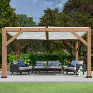 Outdoor patio lounge under wooden pergola with cushioned seating, candle holders, lanterns, and garden backdrop.