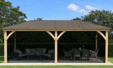 Rectangular wooden gazebo with metal roof, lounge and dining areas on paved garden surface