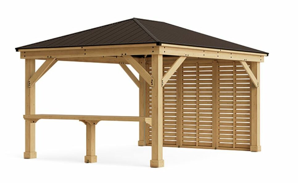 This image shows a wooden gazebo or pavilion designed for outdoor use.

Here are the key features:

Structure: It is constructed from light-colored wood (possibly cedar or pine). The frame consists of sturdy vertical posts and horizontal beams, reinforced by diagonal braces in the front.

Roof: It has a hip roof with a dark, possibly brown or bronze-colored metal or shingle covering.

Walls/Sides:

The right side and back are enclosed with slatted wooden panels that provide partial privacy and shade while still allowing airflow.

The left and front sides are open.

Counter/Bar: A horizontal counter or bar surface is built into the lower section of the front opening, supported by two wooden legs, suggesting it could be used as an outdoor bar, serving area, or prep space.

Overall, it appears to be a modern, functional, and aesthetically pleasing outdoor structure, perhaps used for entertaining or as a covered outdoor kitchen/dining area.