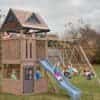 Wooden outdoor playset with a peaked-roof structure, slide, climbing wall, ladder, and swing set, with eight children actively playing in a grassy backyard surrounded by autumn trees in red, orange, and yellow foliage.