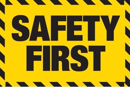 A graphic warning sign with a solid yellow background. The text "SAFETY FIRST" is centered in large, bold, black capital letters, stacked in two lines. The sign is framed by a border of black and yellow diagonal stripes, typical of hazard or caution tape.